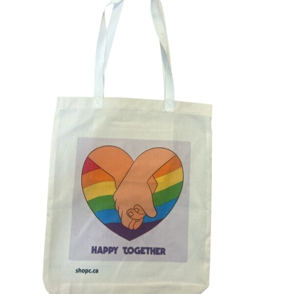 White cotton tote bag featuring two hands reaching for each other with a rainbow heart in the background—symbolizing LGBTQ+ love, support, and unity.