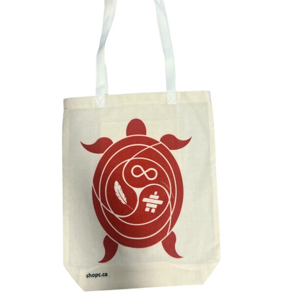 White cotton tote bag featuring a turtle graphic filled with Indigenous-inspired symbols: a feather, an infinity sign, and an Inukshuk—printed in clean, culturally respectful detail.